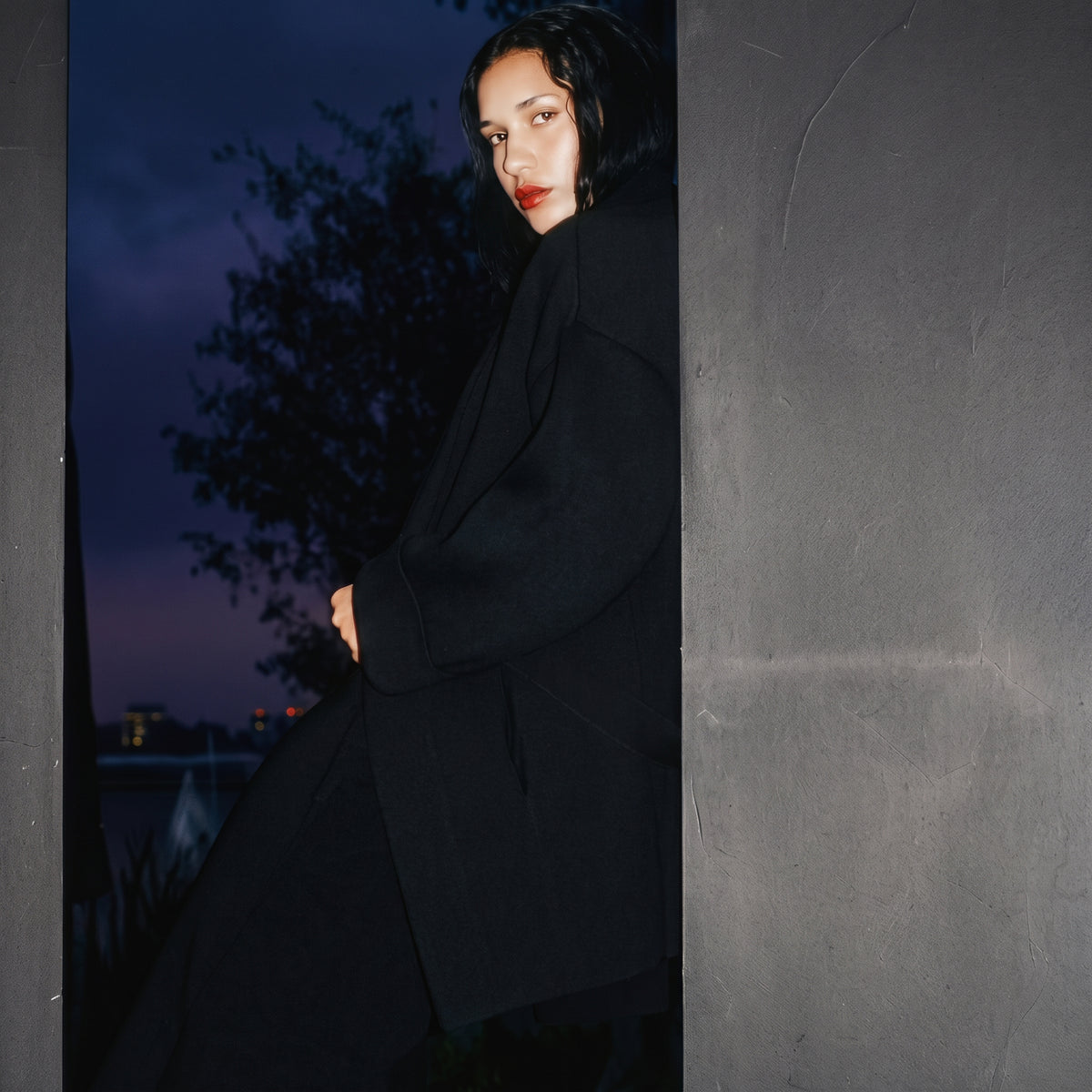 STANDISH. editorial, a model leaning against wall wearing carbon black tailored knitwear