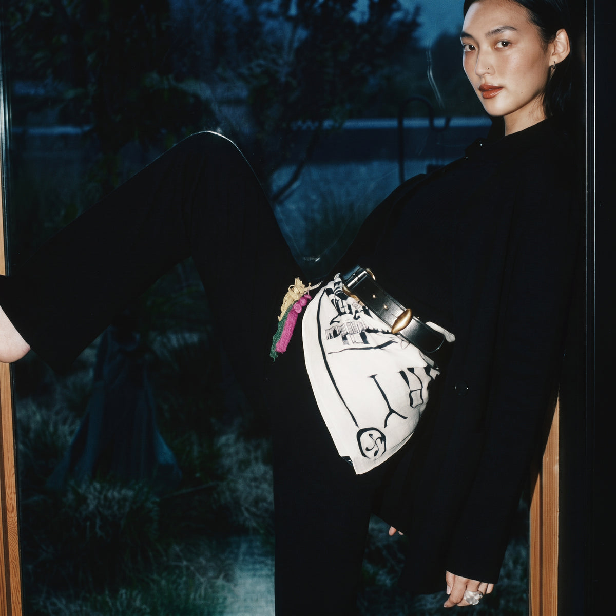 STANDISH. editorial, a model seated in a window pose wearing carbon black tailored knitwear
